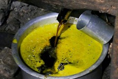 Nella fabbrica che estrae l'olio dai semi di senape, la pressa schiaccia i semi precedentemente tostati, facendone uscire l'olio che viene raccolto in un contenitore di alluminio. Villaggio di Khokanà, Nepal 2018.