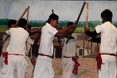 Un momento della danza dei bastoni, tipico ballo tradizionale della cultura Tharu: i ballerini utilizzano dei bastoni che battono ritmicamente l'uno contro l'altro tra di loro seguendo il ritmo dei tamburi e danzando in tondo (mimano il combattimento rituale ma il bastone non deve colpire e neppure sfiorare l'avversario, esso viene scagliato con forza a colpire il bastone impugnato dal "nemico" seguendo il ritmo della musica). Villaggio di Sauraha, Chitwan National Park, Nepal 2018.