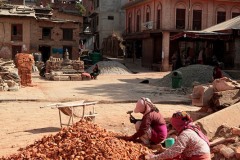 Due donne manovali Newari spaccano, accovacciate sulla strada, le pietre ed i mattoni con la mazzetta, villaggio di Bungamati, Nepal 2018.