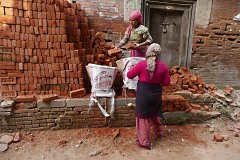 Si caricano i mattoni pieni all'interno del "Doko", la grande cesta che poi verrà issata dalle donne manovali sulla schiena ed ancorata alla fronte con una lunga fascia, Villaggio di Kirtipurdurante la ricostruzione post terremoto, Nepal 2018.
