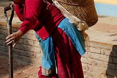 Lo sforzo spaventoso di questa donna Tamang che, sorreggendosi con un braccio alla pala conficcata nel cumulo di cemento e sabbia, solleva il pesantissimo "Doko" (la grande cesta colma di sabbia e cemento) sulle spalle per trasportarlo a piedi per ben quattro piani, Villaggio di Chapagaon, Nepal 2018.