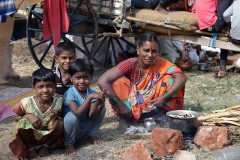 Nel grande accampamento alle porte del villaggio di Saundatti questa mamma hindu sta cucinando il pranzo con il fuoco a legna: accanto ha i suoi tre bambini, da sinistra a destra Bhairavi, Chitragandha e   Amod. Regione del Karnataka, India 2015.