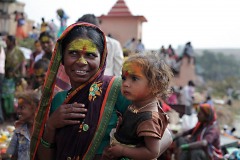 Ritratto di una giovane donna Hindu che tiene in braccio la sua bambina di nome Amodini: entrambe sono contrassegnate sulla fronte con la polvere di curcuma e di kum kum in onore della Dea Yallamma. Dintorni del Tempio dedicato alla Divinità, villaggio di Saundatti, Regione del Karnataka, India 2015.