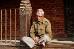 Un anziano uomo nepalese appartenente all'etnia Gurung, medita (concentrato sui suoi pensieri) mentre è seduto a gambe incrociate sull'uscio della sua abitazione a Patan, Nepal 2018.