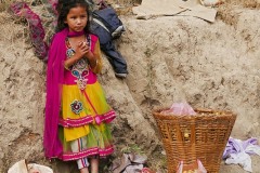 Una deliziosa bambina Gurung, elegantemente vestita, vende la frutta raccolta nel terreno della sua famiglia nel mercato del villaggio di Panauti (ha portato a piedi, da sola, la grande cesta piena di frutta sulla schiena per diversi chilometri), il suo nome è Sita Sapkota, Nepal 2018.