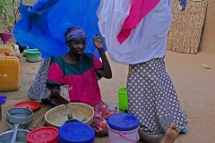 Mentre la mamma prepara il pranzo, la figlia le pone il velo sulle spalle, etnia Haoussa, villaggio Mouja, Niger 2019