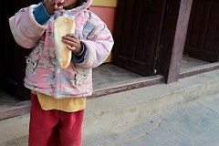 "Due calzini"...una bambina nepalese appartenente all'etnia Newari indossa due calzini di colore diverso mentre si gusta la merenda, Bandipur, Nepal 2018