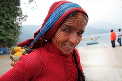 Una donna appartenente all'etnia Sherpa vende mandarini che trasporta sul "Doko", una grande cesta che viene issata sulla schiena mediante degli spallacci intrecciati con resistenti fibre vegetali o corde e ancorata alla fronte con una lunga fascia. A spanne la sua schiena dovrebbe sopportare un peso di oltre 30 chilogrammi. Lungolago di Phewa Tal, Pokhara, Nepal 2018