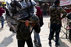 Nella periferia di Kathmandu un uomo Sherpa trasporta sulle spalle un peso incredibile aiutandosi con una fascia posta sulla testa, Nepal 2018.