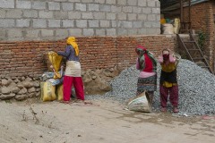 In un cantiere del villaggio di Chapagaon, tre donne appartenenti all'etnia Sherpa caricano sulle loro grandi ceste (dal nome "Doko") il pietrisco che trasporteranno per vari piani a piedi: è un lavoro massacrante e pericoloso. Nepal 2018.