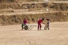 Anche i bambini Tamang lavorano all'interno del cantiere: qui il fratello più grande aiuta la sorellina a caricare sulla carriola un pesante sacco contenente sassi, dintorni del villaggio di Chapagaon, Nepal 2018.