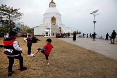 Il seguace di Bruce Lee: un bambino nepalese di etnia Thakali gioca con i suoi amici nel piazzale antistante la Pagoda della Pace nel Mondo. Questa costruzione fu creata su uno stretto rilevo collinare che domina il lago Phewa Tal, dai monaci buddhisti giapponesi, Pokhara, Nepal 2018
