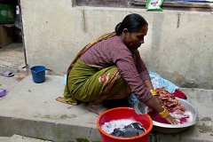 Una donna Thakali lava a mano i vestiti all'interno delle bacinelle sull'uscio della sua abitazione, da notare l'eleganza che la contraddistingue: indossa bracciali, orecchini e cavigliera pur svolgendo un lavoro pesante. Villaggio di Manang, Nepal 2018.