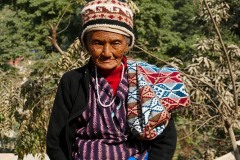 Una anziana donna nepalese appartenente all'etnia Thakali indossa i vestiti tradizionali:  il suo viso bruciato dal sole e le sue mani non certamente appena uscite dalla manicure, testimoniano il duro lavoro svolto durante la sua vita nei campi. I Thakali sono originari della Valla del Kali Gandaki, nel Nepal centrale, ed un tempo svolgevano un ruolo importante nel commercio del sale tra il subcontinente indiano ed il Tibet, ora li si incontra prevalentemente lungo la catena montuosa dell'Annapurna. In origine professavano la fede religiosa buddhista ma negli ultimi anni la maggioranza ha abbracciato in modo pragmatico l'hinduismo. Dintorni del villaggio di Pachabhaiya, Nepal 2018.