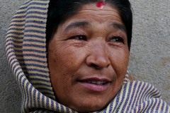 Una donna nepalese di etnia Thakali si avvolge nel suo "Saree", un capo d'abbigliamento antichissimo, costituito da un lungo drappo che viene avvolto intorno al corpo. Nella partizione dei capelli mostra il "Maang" tracciato con il kumkum (polvere di curcuma addizionata a calce spenta) che mostra a tutti il suo stato di donna sposata. Villaggio di Phedi, Nepal 2018.