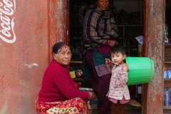Un bambino appartenente all'etnia Thakali gioca con un secchio nelle vicinanze della bottega gestita dalla mamma ed accanto a lui vi è la nonna materna, entrambi mi osservano curiosi. Villaggio di Dhulikhel, Nepal 2018.
