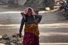 Tra le macerie degli edifici crollati a causa del terribile terremoto nel 2015, questa anziana donna Tharu rientra faticosamente a casa dopo il duro lavoro svolto in campagna: è evidente la sofferenza ad ogni passo che le si legge sul volto, villaggio di Sauraha, Chitwan National Park, Nepal 2018.