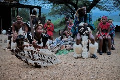 I guerrieri Zulu, accompagnati da giovani ragazze, si apprestano ad iniziare le danze tribali tradizionali, Villaggio Shakaland, Provincia del KwaZulu-Natal, Sud Africa 2012