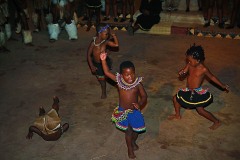 Anche i bambini Zulu si cimentano nella danza tradizionale "Ngoma" saltando e compiendo capriole in un momento di pausa dei ballerini adulti, Villaggio Shakaland, Provincia del KawZulu-Natal, Sud Africa 2012