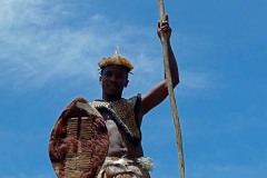 Il saluto di un guerriero Zulu dall'alto della piattaforma in legno dove fa la guardia all'ingresso del villaggio, Villaggio Lesedi, Sud Africa 2012
