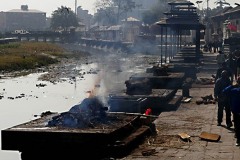 L'interminabile fila di Ghat che costeggia il fiume sacro Bagmati, purtroppo pieno di immondizia, maleodorante ed inquinato: ciònonostante è considerato l'equivalente, in Nepal, del grande fiume sacro  Gange a Varanasi, in India. Questo è il sito più importante per i rituali di cremazione della città di Kathmandu. Qui i corpi dei defunti vengono avvolti nei sudari ed adagiati delicatamente lungo la sponda del fiume, per poi essere posti su di una pira di legna ed essere cremati. La celebrazione del funerale viene condotta in modo sorprendentemente dignitoso, quasi distaccato. Pashupatinath è un luogo di grande intensità emotiva che spinge chiunque, anche i non credenti, a meditare sulla morte e la caducità della nostra esistenza. Kathmandu, Nepal 2018.