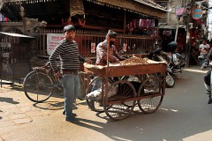 Nell'affollato e caotico incrocio di Asan Tole un avventore nepalese acquista le arachidi tostate da un venditore con il caratteristico carretto a quattro ruote, Kathmandu, Nepal 2018