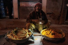 L'incrocio di Asan Tole al tramonto inoltrato: un venditore di spezie illumina con la sua torcia la polvere di curcuma e di zenzero che tiene dentro due grandi tinozze di alluminio, Kathmandu, Nepal 2018