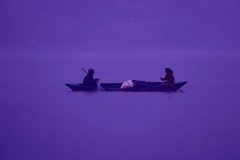 Due pescatori (marito e moglie di etnia Thakali) sono avvolti dall'atmosfera magica dell'alba sul lago di Phewa Tal: le sfumature di rosa, violetto e blu si mescolano con la bruma del primo mattino creando un'atmosfera da sogno, Pokhara, Nepal 2018.