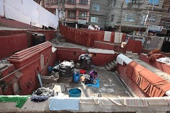 Cheetrapati, un quartiere di Kathmandu dove si concentrano le lavanderie a cielo aperto: uomini e donne, dopo aver lavato a mano i diversi capi di abbigliamento (anche all'interno di antiche cisterne), li stendono sull'erba o su lunghi fili appositamente fissati a pali di legno per farli asciugare. Kathmandu, Nepal 2018