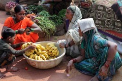 Dhanyata, una giovane mamma Hindu con il suo bambino, contratta nel mercato di Saundatti per l'acquisto di un casco di banane. Regione del Karnataka, India 2015.