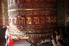 Bambini nepalesi, come tutti i bambini del mondo, giocano divertendosi tantissimo nel far girare l'enorme strumento di preghiera buddista utilizzato per la crescita spirituale e la guarigione denominato Ruota della legge ("Chokhor"), aggrappandosi e girando come se fosse una giostra e, con il proverbiale equilibrio dei nepalesi, nessun adulto li rimprovera, Stupa di Bodhnath, Valle di Kathmandu, Nepal 2018
