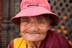Una anziana donna nepalese all'ingresso dello Stupa di Bodhnath: le donne hanno vita dura in Nepal; esse lavorano di più e più a lungo degli uomini con una paga nettamente inferiore; possono migliorare la loro posizione sociale solo se riescono a procreare un figlio maschio che garantisca la progenie del marito; il loro tasso di alfabetizzazione è più basso rispetto a quello dei maschi; la società nepalese è fortemente patriarcale (fatte rare eccezioni come nel caso delle comunità himalayane degli Sherpa dove le donne vivono in una società matriarcale), le donne sono le ultime a mangiare e le prime ad abbandonare gli studi nel caso di ristrettezze economiche della famiglia di origine, nei giorni del ciclo vengono spesso isolate ed allontanate perchè considerate impure; inotre la tratta delle giovani donne nepalesi costituisce un gravissimo problema nelle zone rurali più povere, sono ridotte in schiavitù e vendute per lavorare come domestiche, operaie o prostitute, si stima che ogni anno dalle 10.000 alle 15.000 ragazze siano oggetto di questo traffico ignobile. Kathmandu, Nepal 2018