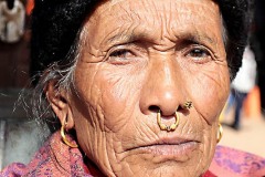 Anziana donna dell'Etnia Tamang indossa un tradizionale orecchino nasale (inserito con un piercing "Septum" che fora la base del setto nasale) che indica il suo alto rango sociale, oltre all'orecchino posto sulla narice sinistra (per la medicina ayurvedica, la narice viene associata agli organi riproduttivi femminili, quindi dovrebbe aiutare la donna che lo indossa a partorire in modo più semplice), dintorni di Durbar Square, Kathmandu, Nepal 2018