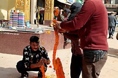 Nel piazzale antistantelo Stupa di  Bodhnath, lo Stupa più grande di tutta l'Asia, si confezionano ghirlande di fiori da utilizzare durante le cerimonie religiose, dintorni di Kathmandu, Nepal 2018