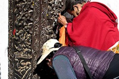 All'ingresso del Tempio di Shiva dell'Indra Chowk (il cortile che prende il nome dall'antica divinità vedica Indra), due devote nepalesi si inginocchiano pregando ed offrendo fiori alla Dinità, Kathmandu, Nepal 2018