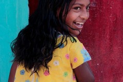 Il sorriso contagioso di questa bambina Hindu dal nome Cauvery entra con formidabile intensità nell'obiettivo della mia macchina fotografica prima di dileguarsi al di là del portone di ingresso della sua casa. Villaggio di Belur, regione del Karnataka, India 2015.