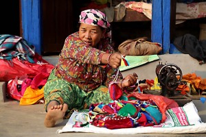 Nella cittadina Newari di Bandipur, una donna offre ai passanti le borsette da lei stessa confezionate con una vecchia macchina da cucire manuale, Nepal 2018