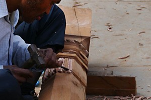 Nello splendido Palazzo Reale di Patan fervono i lavori per la ricostruzione post terremoto: qui un intagliatore di legno realizza con lo scalpello ed il martello le antiche decorazioni sulle colonne in legno duro tropicale (Shorea robusta) che verrà posta nella parte strutturale dell'edificio. E' un mestiere che si tramanda da generazione in generazione: quando questi artigiani ricevono delle commissioni diverse dalla ricostruzione di edifici già esistenti, ascoltano con attenzione le esigenze dei committenti, realizzando poi schizzi su carta fatta a mano che riproducano le indicazioni ricevute e, una volta approvati, riproducono le immagini e le decorazioni intagliandole sul legno. Nepal 2018.