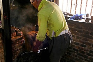 In una fabbrica artigianale si estrae l'olio dai semi di senape: qui il proprietario inserisce i semi appena tostati dentro un grande recipiente che poi svuoterà nella pressa che, schiacciandoli, farà uscire l'olio. Il lavoro viene svolto ancora del tutto manualmente in modo tradizionale e con macchinari realizzati ingegnosamente dall'uomo. Villaggio di Khokanà, Nepal 2018.