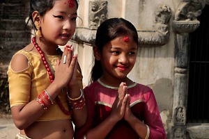 Il ritratto di due bambine nepalesi di etnia Newari: la bambina vestita a festa che indossa gli orecchini e monili vari (di nome Bineta) ha appena festeggiato, accompagnata dalla sorella minore, una cerimonia molto particolare. Si tratta di un matrimonio di "gruppo" in cui centinaia di bambine Hindu e Buddhiste celebrano un matrimonio atipico con un "Bael" un particolare albero da frutto. Secondo questa pratica, prima di raggiungere la pubertà, le bambine devono essere sposate ad un albero di Bael, il cui frutto prende il nome di "Aegle". Questo rito si chiama "Ehi" nella lingua locale newari e coinvolge le ragazzine tra i 5 ed i 12 anni. In genere la cerimonia dura due giorni: inizia con i rituali di purificazione e si conclude con il "Kanyadan", il momento cruciale in cui il padre "dona" la figlia. Nella cultura newari si crede che i genitori possano conquistarsi un posto in cielo sposando le loro figlie prima di avere le mestruazioni. Secondo la tradizione, il frutto ("Aegle") rappresenta lo sposo (simboleggia l'eterno scapolo Kumar, figlio del Dio Hindu Shiva) ed il matrimonio propiziatorio garantisce alla ragazza di diventare e rimanere fertile. Il frutto prescelto deve essere maturo e succoso e non deve riportare alcun danno. Se risultasse ammaccato, la sposa sarà destinata ad avere un marito brutto ed infedele. In realtà, la ragione più importante alla base di questa pratica, consiste nella credenza che la giovane sposandosi con Kuma, rimarrà pura e casta e non potrà essere considerata vedova anche nel caso che il "vero" marito dovesse venir meno, poichè sarà già sposata con una Divinità. Patan, Nepal 2018.