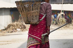 Una donna Newari, appartenente alla casta degli agricoltori ("Vaisya"), rientra dal duro lavoro in campagna stringendo nella mano il manico della zappa e con l'immancabile grande cesta sulla schiena (il "Doko"), villaggio di Bhaktapur, Nepal 2018.
