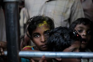 Amshula, Ela e Badriprasad tre bambini Hindu (da sinistra a destra) sono al di là della transenna che permette al corteo dei pellegrini di entrare all'interno del Tempio dedicato alla Dea Yallamma: il loro sguardo incredulo ed interrogativo nell'osservare l'unico occidentale presente al Renuka Yallamma Jatra, testimonia la scarsa o quasi nulla considerazione e conoscenza del mondo cosiddetto civile riguardo questa Festa in onore di una Divinità così importante per centinaia di migliaia di devoti Hindu. Villaggio di Saundatti, Regione del Karnataka, India 2015.