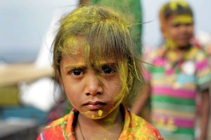 Anche i bambini partecipano alla Festa in onore della Dea Yallamma: anche loro sono ricoperti della polvere ocra di curcuma e rossa di kum kum, tra nuvole gialle e rosse che si addensano nell'aria ad ogni lancio da parte dei pellegrini festanti. Questa bimba dallo sguardo intenso e quasi corrucciato si chiama "Shaila" (figlia della collina). Dintorni del villaggio di Saundatti, Regione del Karnataka, India 2015.