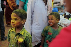 I bambini sono tra i protagonisti delle celebrazioni in onore della Dea Yallamma durante il Renuka Yallamma Jatra: il lancio delle polveri colorate di curcuma e di kum kum, la musica dei tamburi, i canti propiziatori, le danze sfrenate li coinvolgono e li divertono. Questi due bambini di nome, rispettivamente (da sinistra a destra), Ajit e Chandresh, si stanno divertendo un mondo a guardare il corteo dei pellegrini festante e rumoroso che si dirige verso il Tempio. Villaggio di Saundatti, Regione del Karnataka, India 2015.