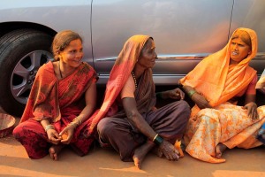 Queste tre donne Hindu scherzano tra di loro mentre, sedute a terra con le gambe incrociate (posizione che prende il nome di "Sukhasana"), si prendono una pausa durante la processione in onore della Dea Yallamma. Villaggio di Saundatti, regione del Karnataka, India 2015.