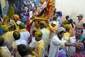 I pellegrini festanti portano a braccia la statua della Dea Yallamma per introdurla nel Tempio dedicato alla Divinità: nugoli di sottile polvere gialla e rossa (curcuma e kum kum) si addensano nell'aria cospargendo vestiti, capelli, strade, pareti. Si innalza prepotentemente al cielo il canto propiziatorio "Udho Udho" scandito dai devoti come saluto nei confronti della Dea. Anche il profumo intenso dell'incenso invade l'aria. Il suono dei tamburi scandisce il turbinio di emozioni, di suoni, di colori e di profumi che riunisce le persone desiderose di uscire dall'ombra, di manifestarsi liberamente, di rivendicare l'attenzione, almeno per questa Festa. Si percepisce un'energia prepotente, formidabile, travolgente, vibrante. Tempio dedicato alla Dea Yallamma, villaggio di Saundatti, Regione del Karnataka, India 2015.