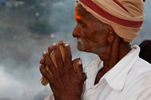 Un anziano pellegrino stringe tra le mani giunte due noci di cocco: questa sua offerta diretta alla Dea Yallamma prende il nome di "Puja" (termine derivato dal sanscrito, che può tradursi in adorazione, culto, offerta che sconfigge il peccato). In tal modo si compie il ciclo della reciproca offerta tra le creature. La vita è sostenuta dallo scambio tra gli esseri, dall'offerta di ognuno nel donare ad altri una parte di sè, dal preservare il valore di qualsiasi forma di esistenza. Tale rito si identifica nel tentativo di porsi in armonia con il ciclo naturale che consente di riscoprire la propria identità con la Divinità, purificando al tempo stesso la propria mente ed i propri sensi sino a condurre al completo abbandono. L'offerta alla Dea Yallamma diviene "Prasada" (termine sanscrito che si può tradurre in grazia, purezza, dono divino) ed ha, come diretta conseguenza della sua assunzione, di produrre una profonda forza, una salda fede, un grande equilibrio, energie positive e infinito amore: non si limita alla sola offerta di cibo ma, bensì a qualsiasi oggetto portato al Tempio o venuto a contatto con la grazia trasformante della Divinità. Dintorni del villaggio di Saundatti, regione del Karnataka, India 2015.