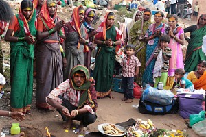 Un gruppo familiare si è riunito, nelle adiacenze del Tempio Yallamma Devi dedicato alla Dea Yallamma per svolgere il rito della "Puja": cibo e acqua sono elementi essenziali della Puja e gli alimenti offerti sono in particolare latte, burro chiarificato, yogurt, zucchero, miele, frutta, riso, dolci, spezie e foglie di piante sacre (come tulsi o betel). Inoltre vengono offerti anche svariati cibi cotti a base di cereali, ortaggi e spezie. Il cibo offerto, dopo essere stato sacralizzato, diviene "Prasada"(che in sanscrito significa "grazia, purezza, dono divino") e viene così offerto ai fedeli presenti al rito. Si crede che la Puja possa generare grandi benefici come la salute, l'armonia, la prosperità, la risoluzione dei problemi, il conforto nella sofferenza, la pace e molti altri. Mentre il cibo, trasformatosi in Prasada, si crede possa produrre in coloro che se ne nutrono, una fede salda, una forza profonda, un notevole equilibrio, infinito amore, e molte energie positive per la salute del corpo e della mente. Villaggio di Saundatti, regione del Karnataka, India 2015.