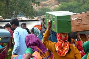 Donne Hindu con le loro valigie sulla testa, i bauli, le borse, si affrettano a raggiungere il luogo dove le attendono i sgangherati autobus con cui sono arrivate a Saundatti e che ora le riporteranno nei loro villaggi di origine. REgione del Karnataka, India 2015.