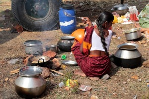 Nell'immenso accampamento sorto ai piedi della collina Yallammagudda che ospita oltre centomila pellegrini, giunti sin qui per partecipare al Renuka Yallamma Jatra (i festeggiamenti in onore della Dea Yallamma), una giovane donna Hindu cucina con il fuoco muovendosi con grande fascino. Dintorni del villaggio di Saundatti, regione del Karnataka, India 2015.